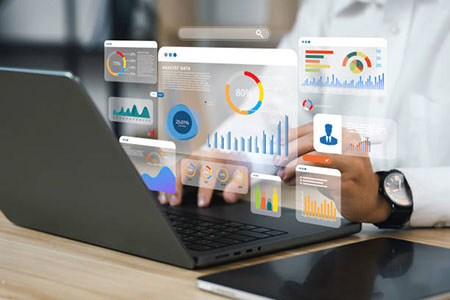 Person typing on laptop with mutliple data graphs shown